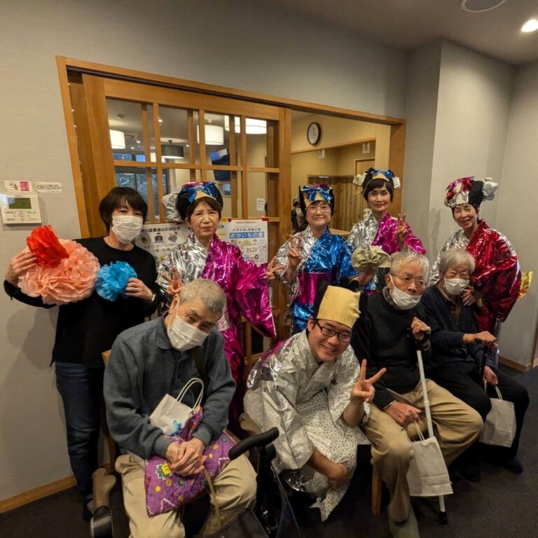 入居者と職員による季節行事。カラフルな衣装と装飾品で楽しく参加する様子。